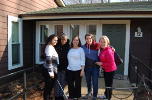 A group of women standing in front of a house.