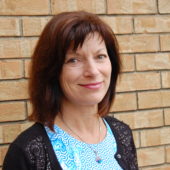 A woman standing in front of a brick wall.