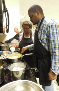 A man and woman cooking food in a kitchen.