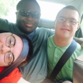 Three young teens in a car all wearing glasses with their seat belts on