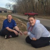 Two people sitting on the side of a road.