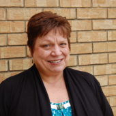 A woman standing in front of a brick wall.