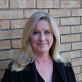 A woman standing in front of a brick wall.