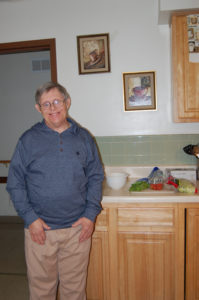 A man standing in front of the kitchen sink.