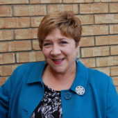 A woman with short hair wearing a blue jacket.