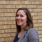 A woman standing in front of a brick wall.