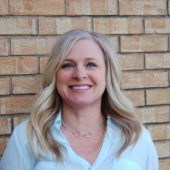 A woman standing in front of a brick wall.