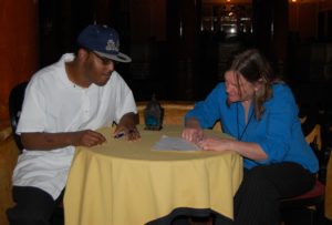 A man and woman sitting at a table writing.