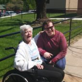A woman sitting next to an older person in a wheelchair.
