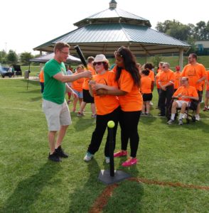 A group of people in orange shirts playing baseball.