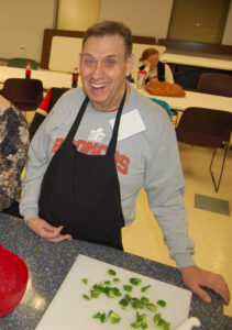 A man smiles while preparing food on the counter.