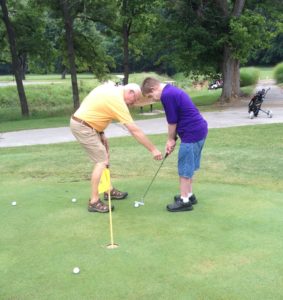 Two men are playing golf on a green.