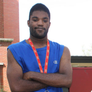 A man with his arms crossed wearing a blue shirt.