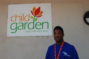 A man standing in front of a child garden sign.