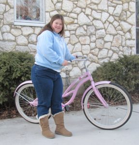 A woman standing next to her pink bike.