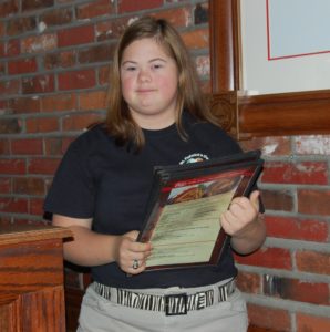 A woman holding a menu in front of brick wall.