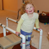 A little girl standing on top of some bars.