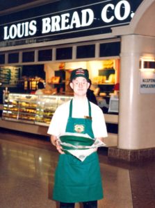 A man holding a tray of food in front of a store.