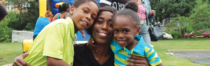 A woman and two children smiling for the camera.