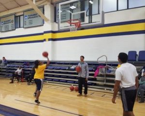 A group of people playing basketball in the gym.