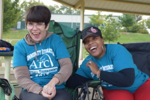 Two women sitting on a bench smiling for the camera.