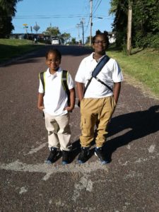 Two boys standing on the side of a road.