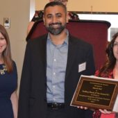 A man and two women holding an award.