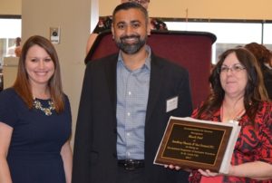 A man and two women holding an award.