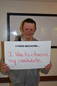 A man holding up a sign that says i vote because.