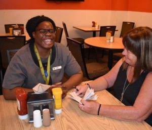 Two women sitting at a table with drinks and food.