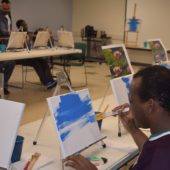 A man painting with his fingers on the side of his face.