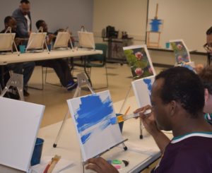 A man painting with his fingers on the side of his face.