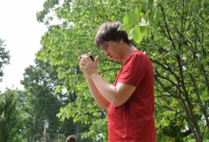 A man in red shirt holding up a camera.