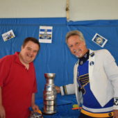 Two men standing next to a trophy.