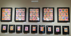 A wall with several frames of different shapes and colors.