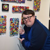 man pointing at his art on the wall