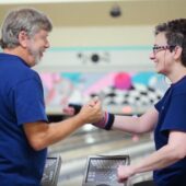 volunteer and participant at bowling celebrating a win with a handshake