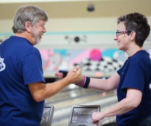 volunteer and participant at bowling celebrating a win with a handshake