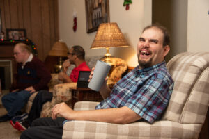 A man sitting on top of a couch holding onto a cup.