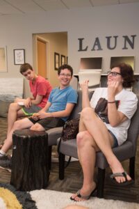 Three people sitting in a room with remotes.
