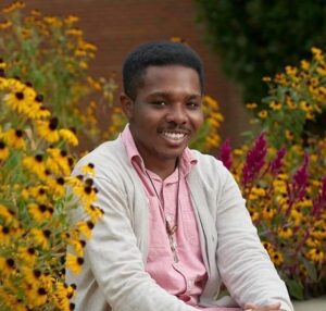 A man sitting in front of flowers and bushes.