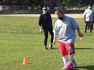 Young man in grey shirt and red shorts playing soccer 