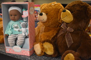 Two stuffed bears are next to a doll.