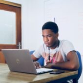 young man sitting at a desk looking at a laptop