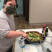 A woman cooks vegetables in a hot plate.