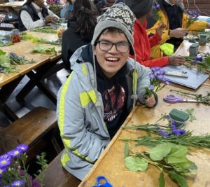 A man sitting at a table with flowers in front of him.