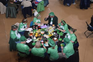 a group of people wearing green sit at a trivia night table