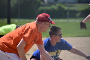 A coach points in the field, showing a softball player what to do.