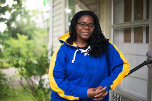A woman standing in front of a house.
