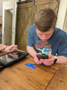 A boy is looking at his phone while sitting on the table.